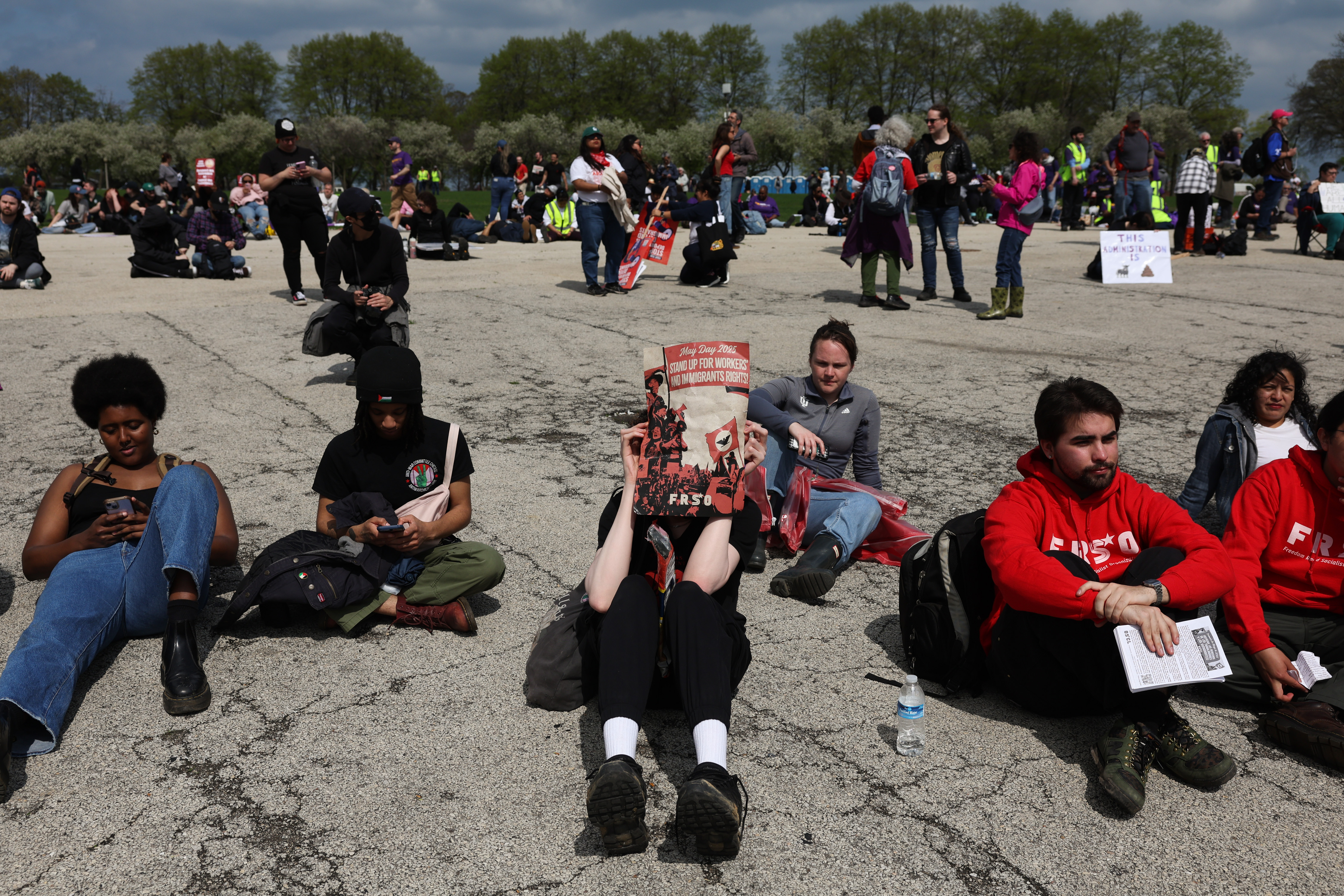 A demonstrator shields their face from the sun while listening to speakers at a rally after a May Day march at Butler Field, May 1, 2025, in Chicago. (John J. Kim/Chicago Tribune)