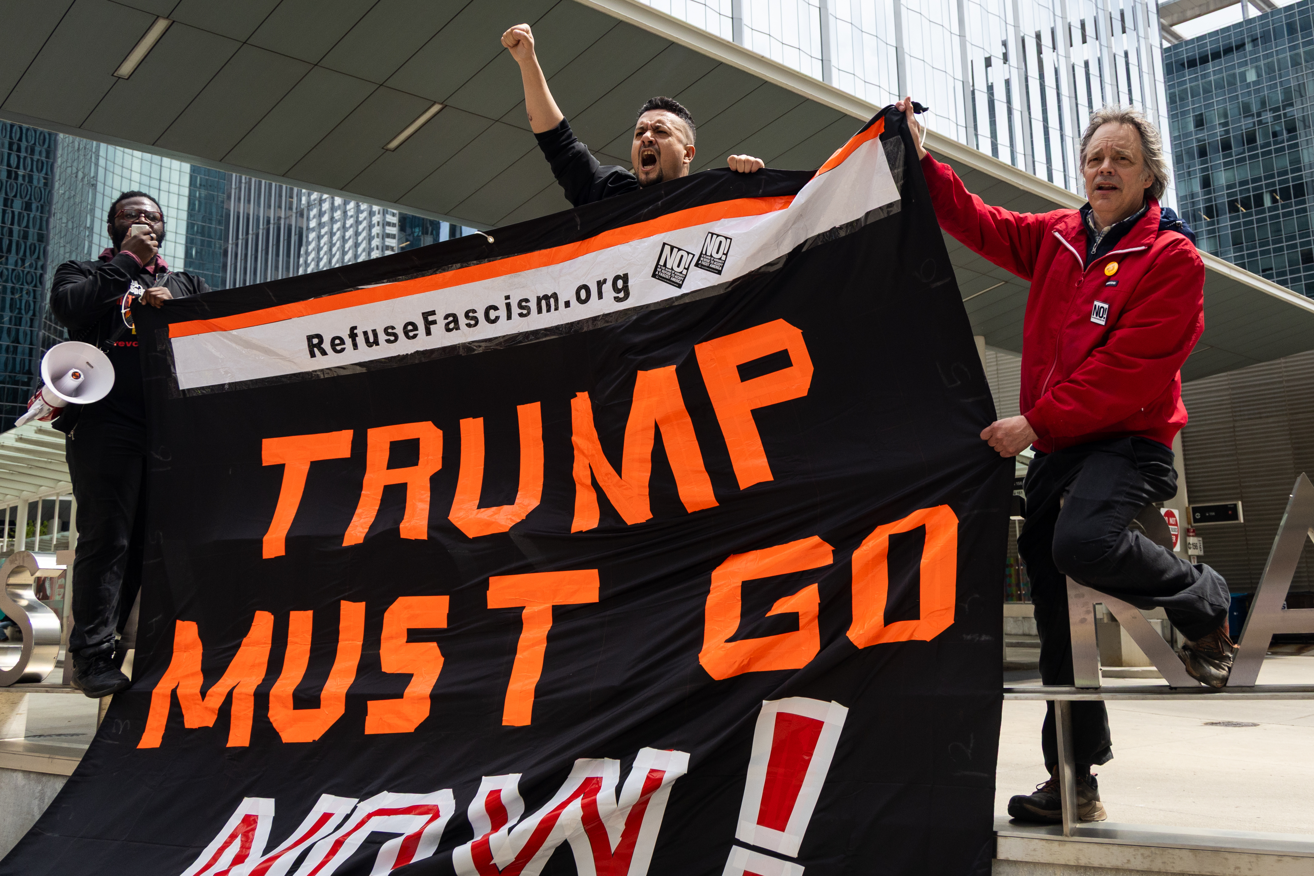 People hold signs along Jackson Boulevard as thousands march from Union Park to Grant Park for the May Day march on May 1, 2025. (Audrey Richardson/Chicago Tribune)