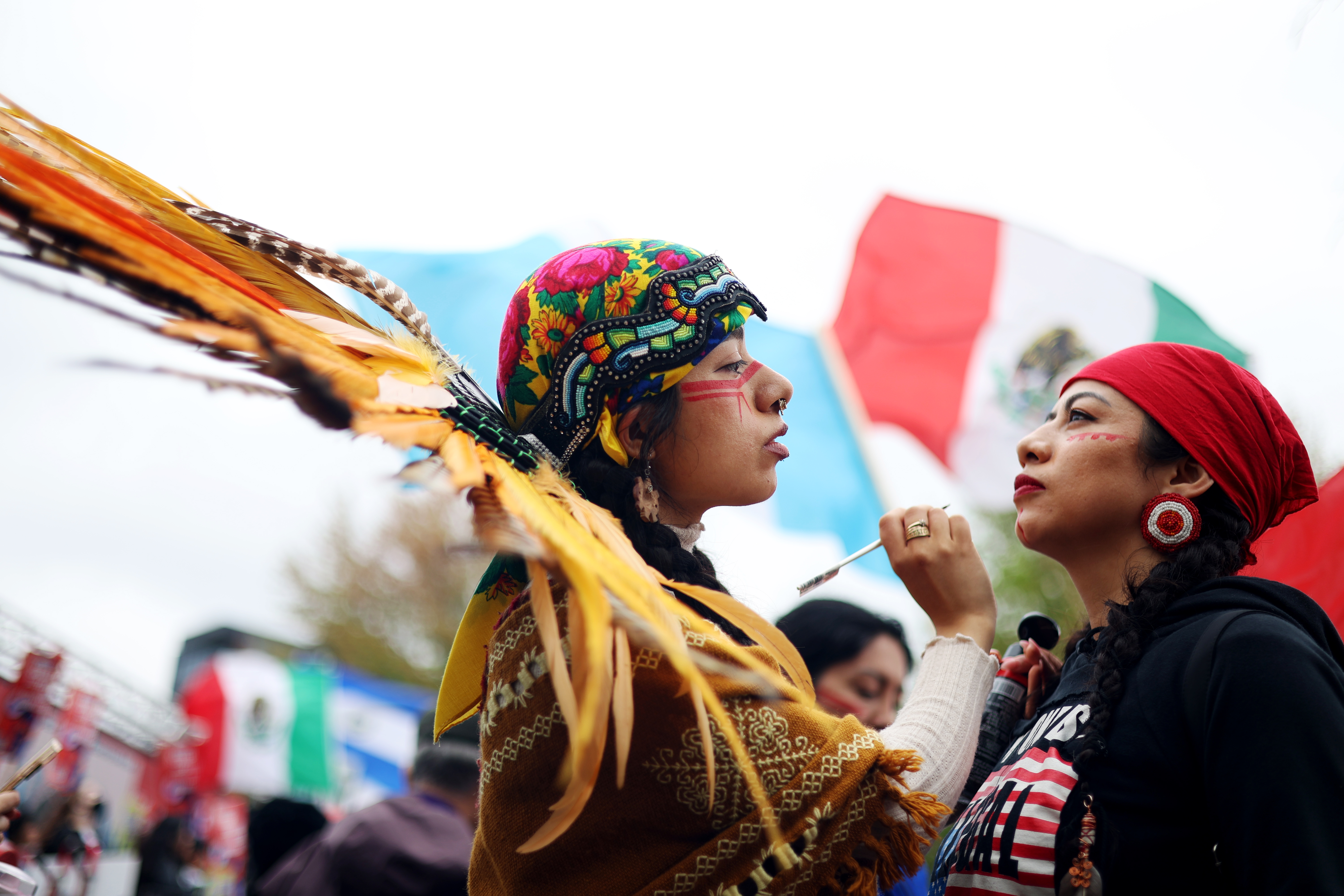 Susana Huitron gets war paint drawn on her face by Selena Sanchez, who is a member of the indigenous Mexica people, as hundreds gather at Union Park for the May Day march, May 1, 2025. (Audrey Richardson/Chicago Tribune)