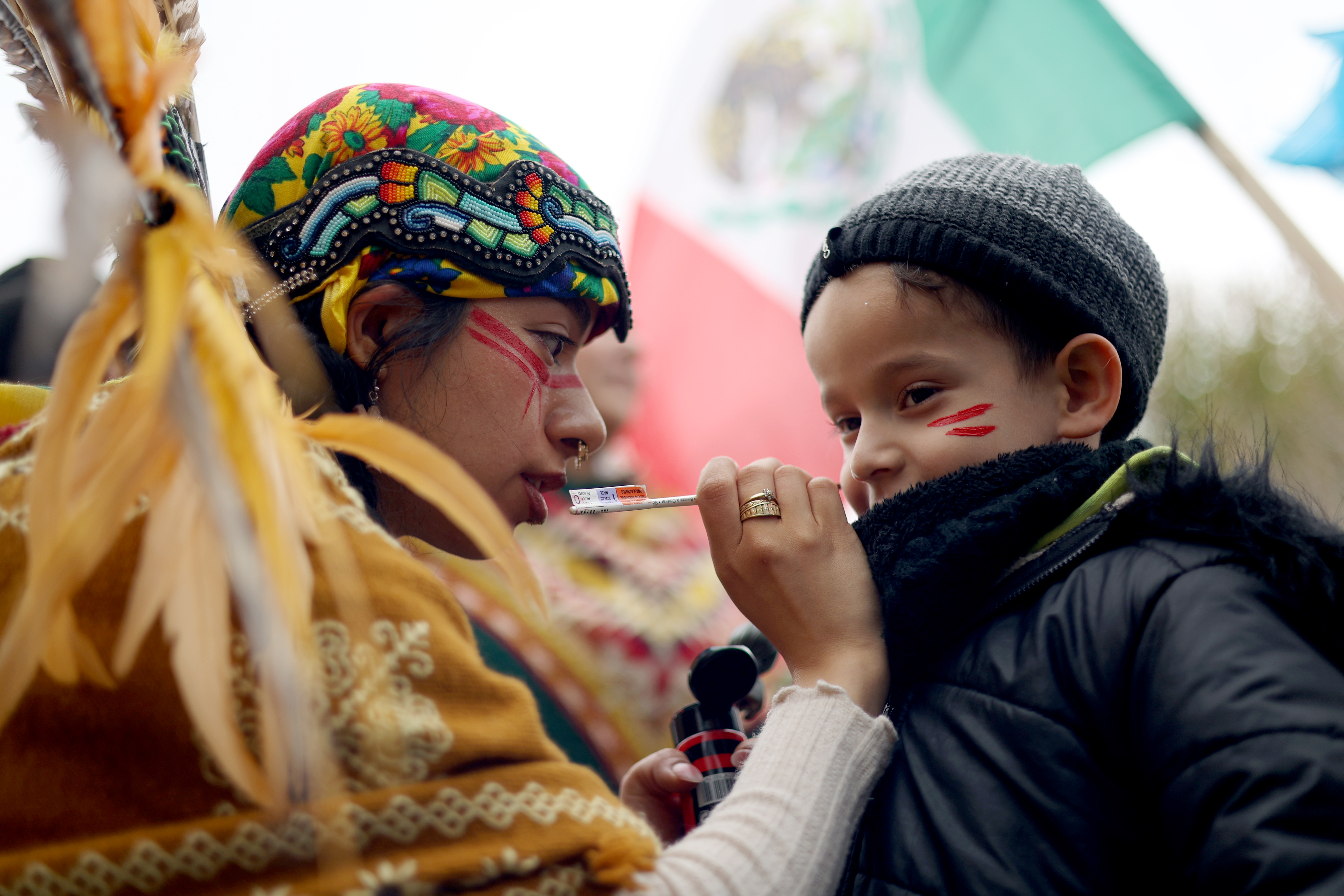 Jaden Palacios, 7, gets war paint drawn on her face by Selena Sanchez, a member of the indigenous Mexica people, as hundreds gather at Union Park for the May Day march, May 1, 2025, honoring working people for International Workers' Day, before marching to Grant Park. (Audrey Richardson/Chicago Tribune)