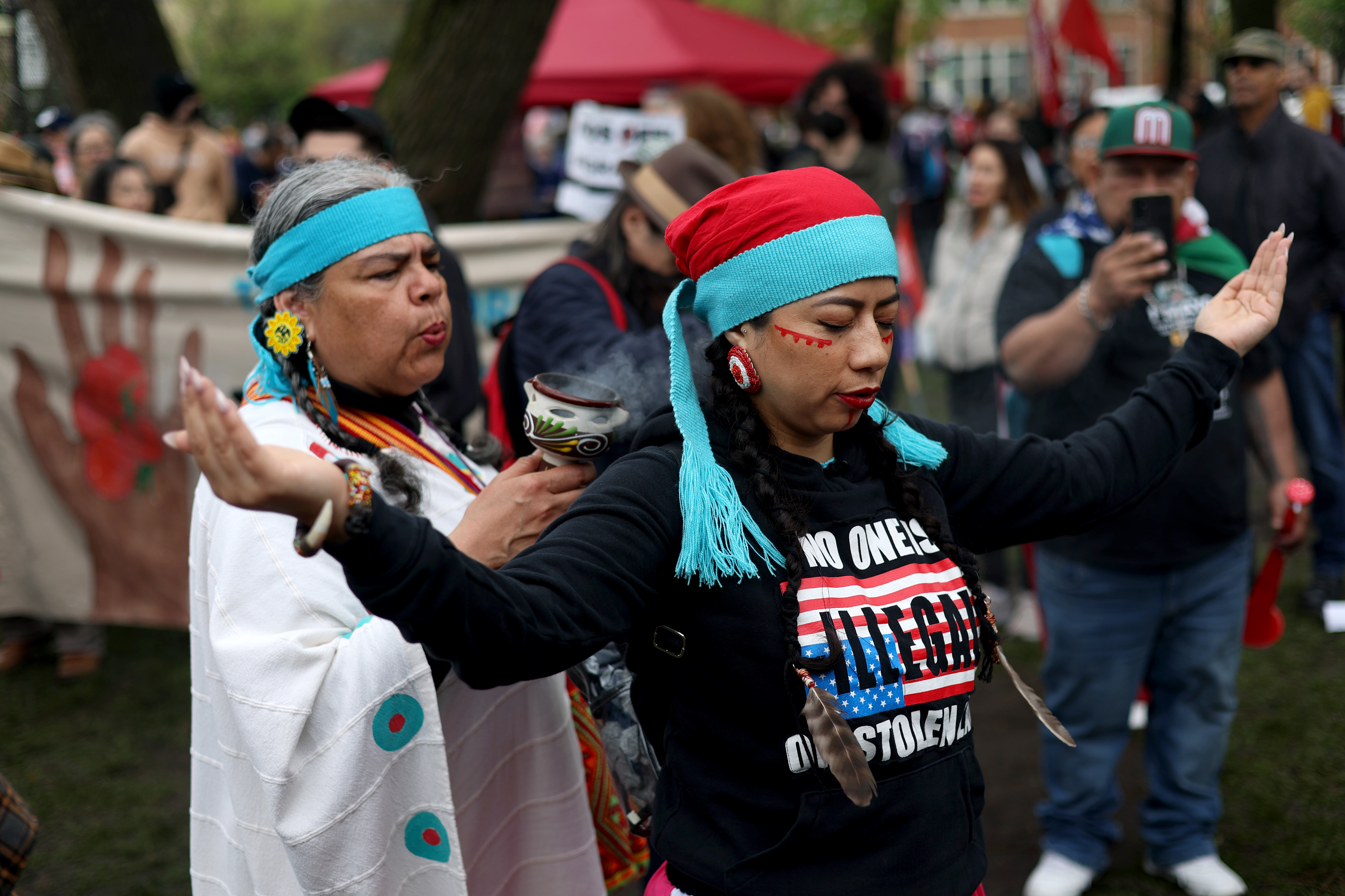 Ollin Kuikatl Tekpatl, left, performs smudging, using medicine to "help harmonize the soul and spirit," on Susana Huitron as hundreds gather at Union Park for the May Day march, May 1, 2025, honoring working people for International Workers' Day, before marching to Grant Park. (Audrey Richardson/Chicago Tribune)