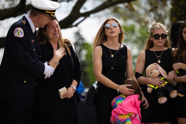 Battalion Chief Scott Shawaluk hugs Kristen Meyer, wife of Capt. David Meyer, among other family members as members of the Chicago Fire Department, the Chicago Police Department, family, and community members attend Meyer's funeral, April 29, 2025, at St. John Brebeuf Church in Niles. Shawaluk is the Meyers' close friend and neighbor. (Audrey Richardson/Chicago Tribune)