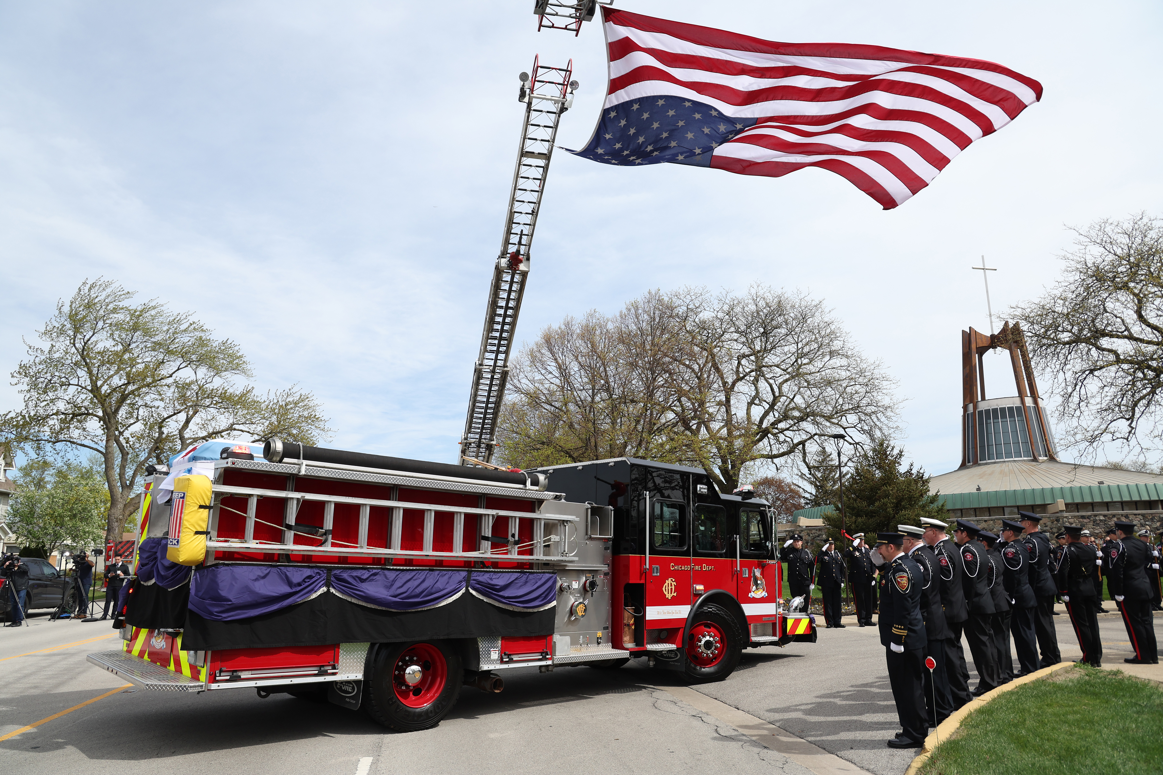 A giant American flag is hung as a Chicago fire truck carrying the casket of fallen Chicago Fire Department Capt. David Meyer heads toward St. John Brebeuf Church in Niles for funeral services on April 29, 2025. (Antonio Perez/Chicago Tribune)