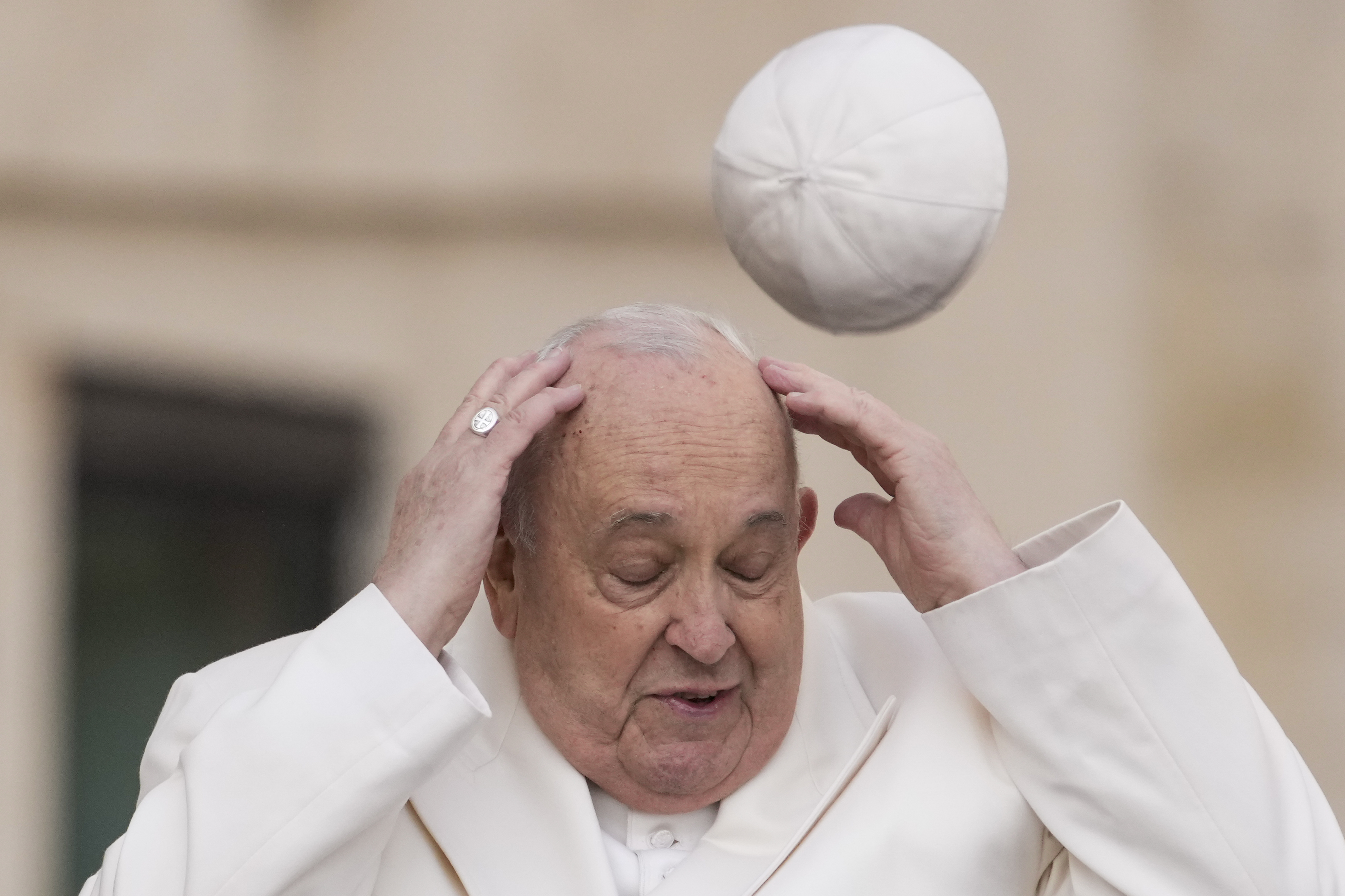 Pope Francis tries to catch his cap as wind blows it away while arriving for his weekly general audience in St. Peter's Square at the Vatican, March 13, 2024. (Andrew Medichini/AP)